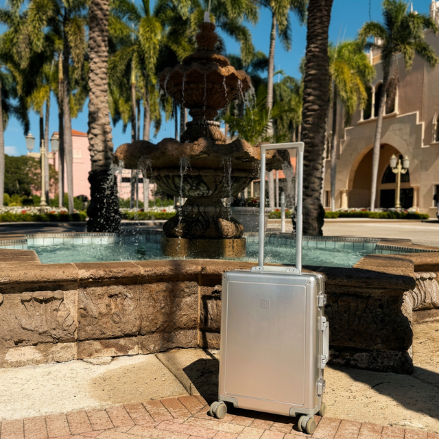 A luxury Loure travel suitcase sitting by a beautiful Miami beachfront. The best luxury luggage for European travel.